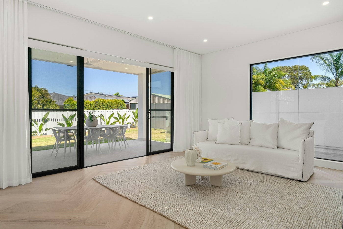 Illustrative white living room opening to a terrace through sliding glass doors
