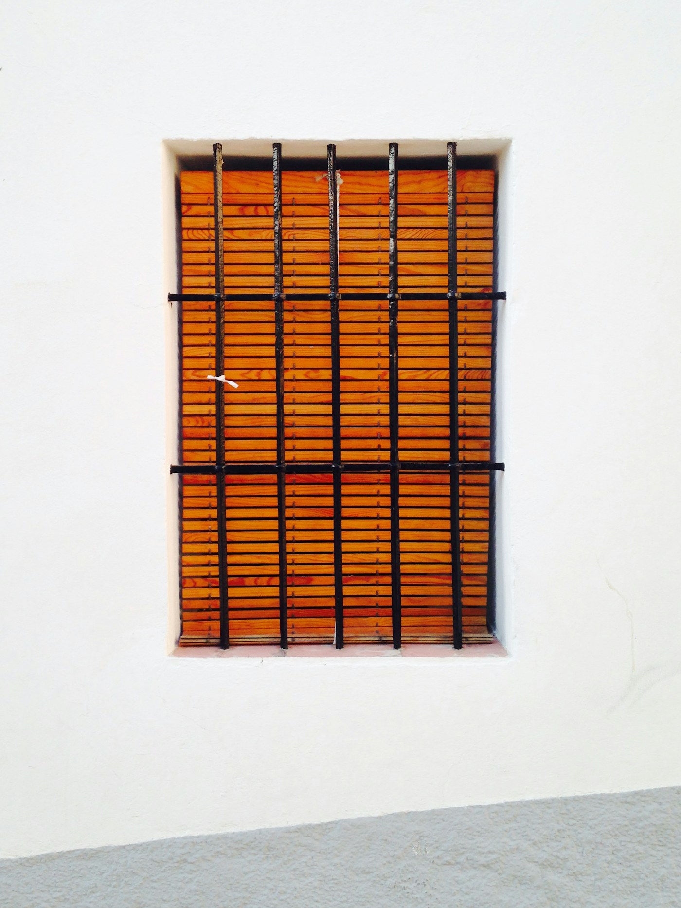 Illustrative black window grille and warm-toned window blinds